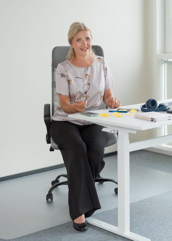 Assistent, prillid käes, suhtlemas büroo laua taga